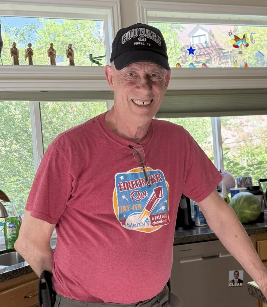 Smiling older adult standing in a home kitchen environment