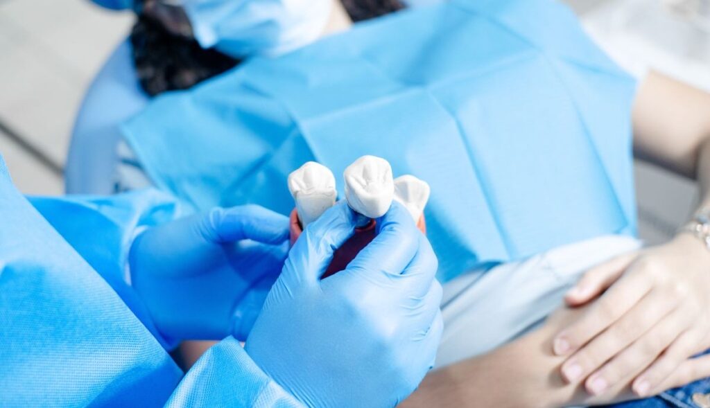 Dental professional holding tooth restorations during a patient consultation