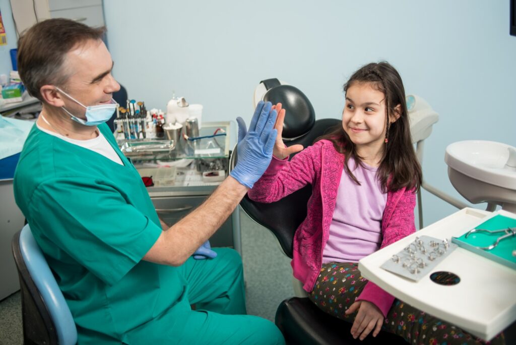 Dentist giving a high-five to a young patient in a dental clinic
